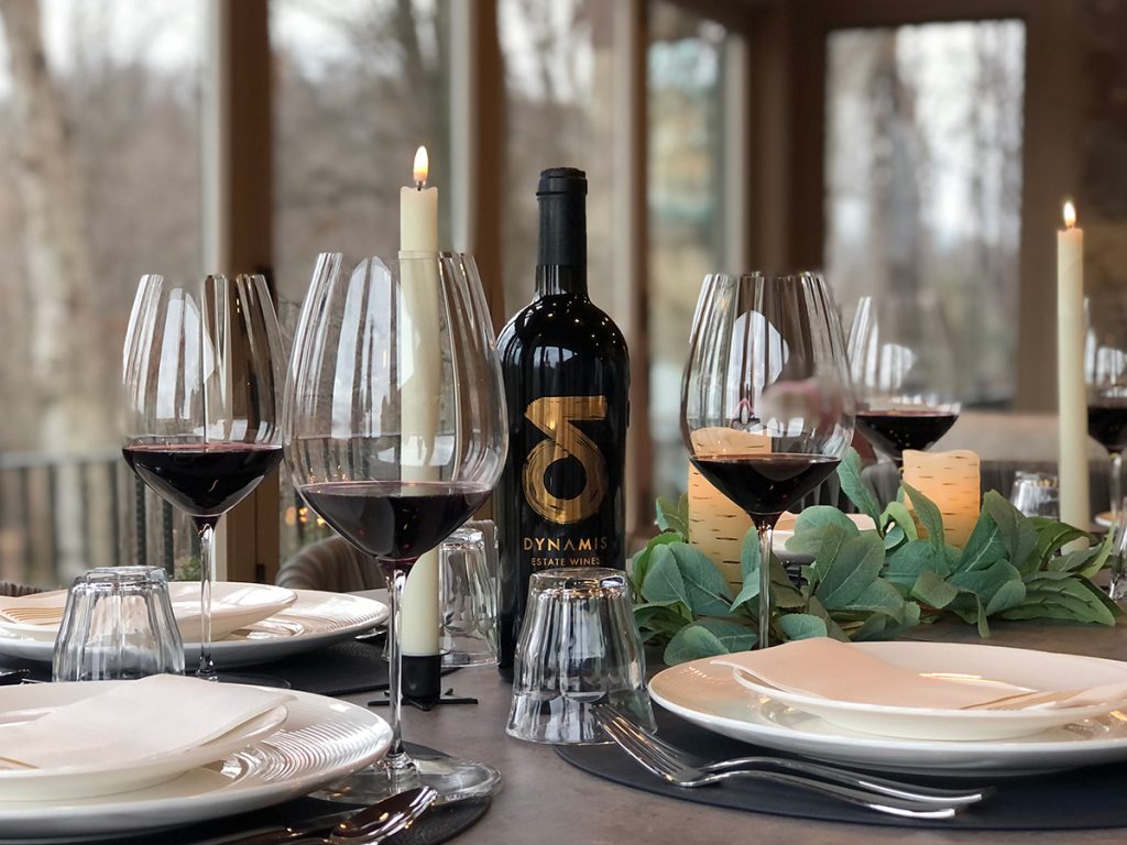 Table Arrangement with red wine glasses and gold labelled Dynamis Estate Wines bottle.