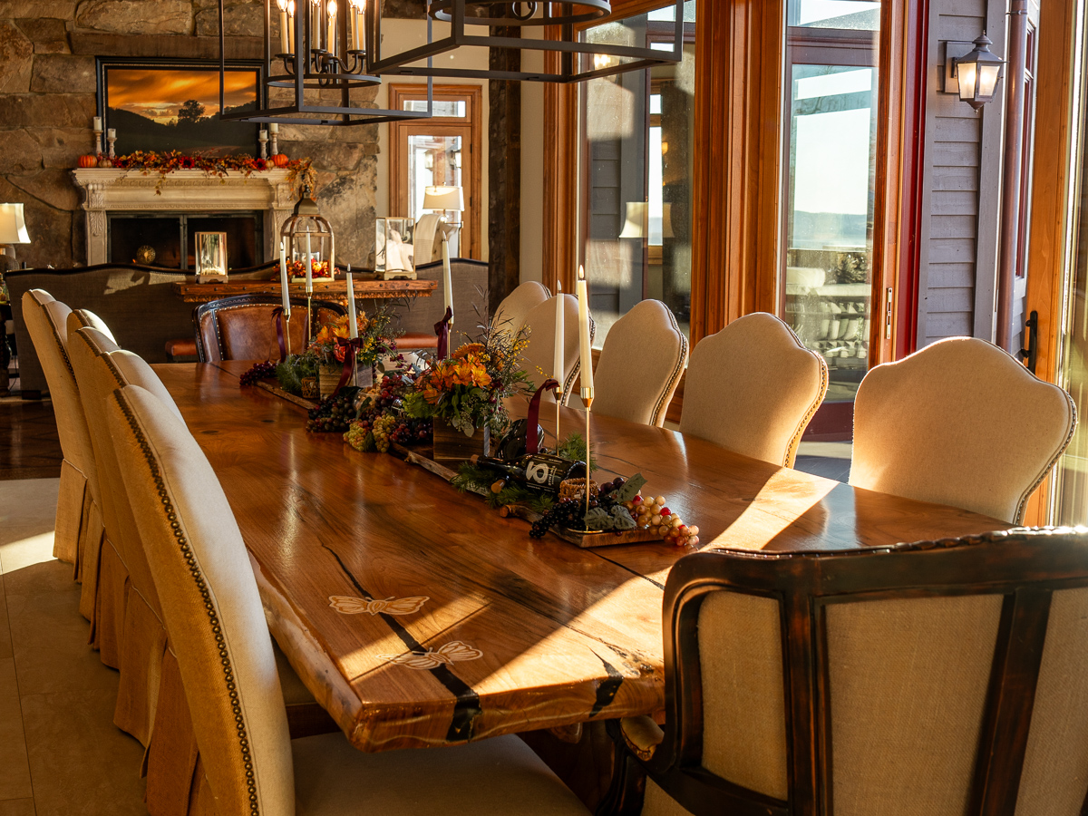 Large wooden table with center display filled with flowers, wine bottles, candles and grapes.