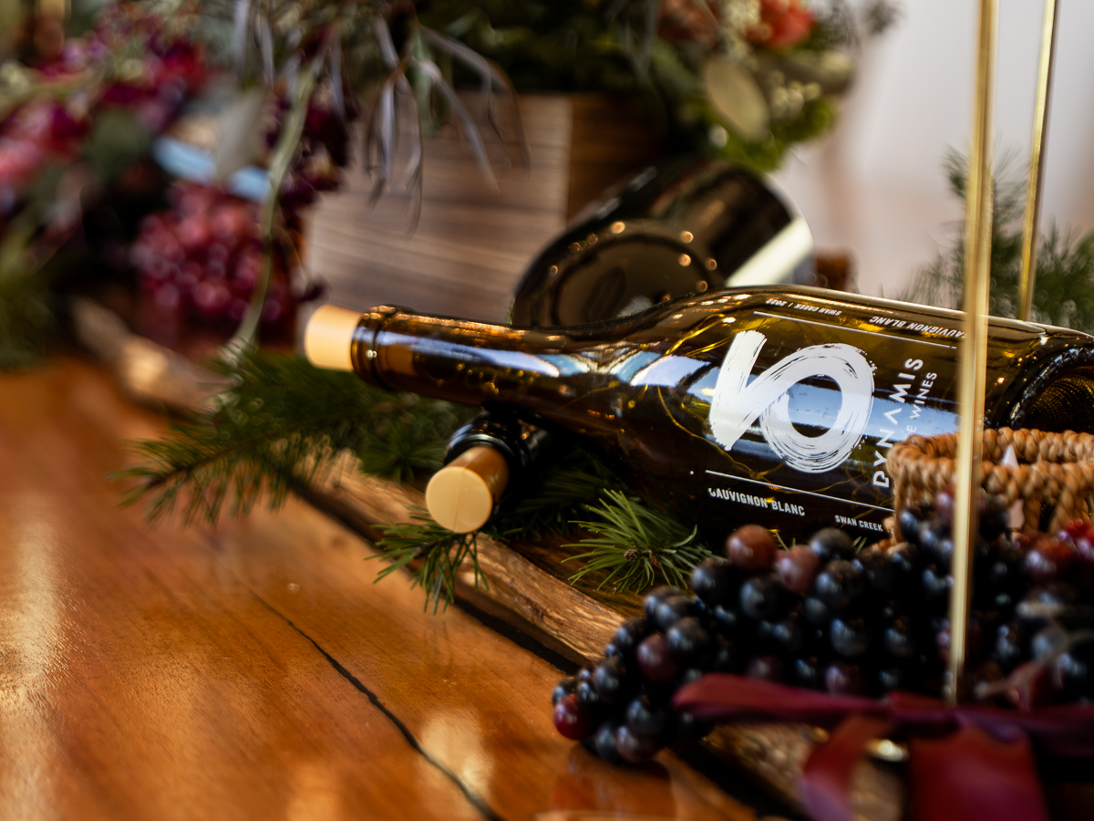 Wine bottle posed on table display with candles, grapes and flowers.