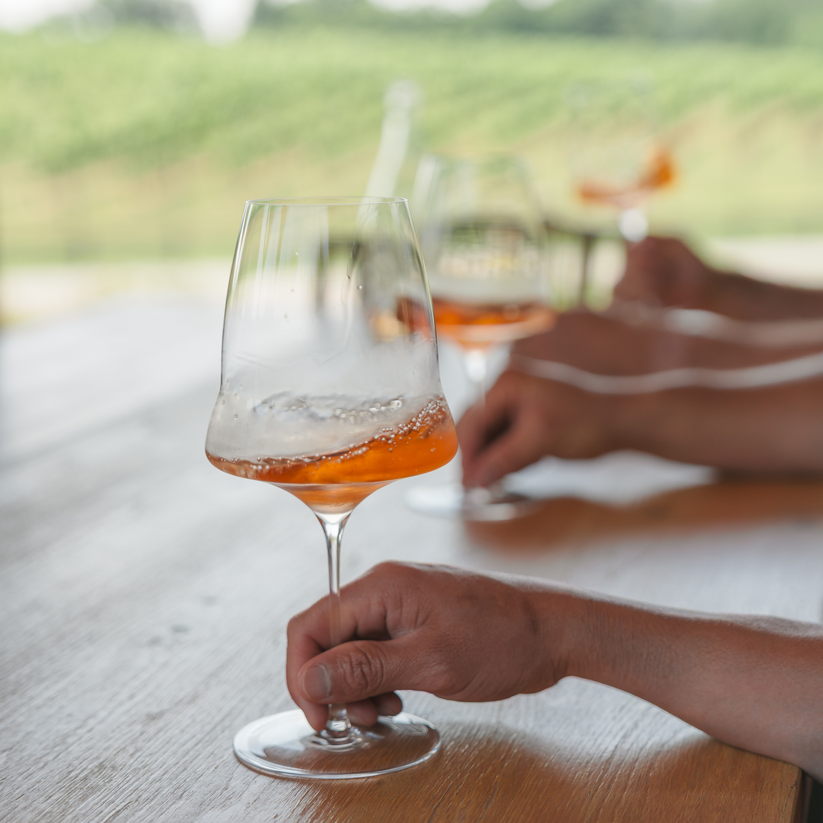 Three hands holding wines glasses with rose in it.